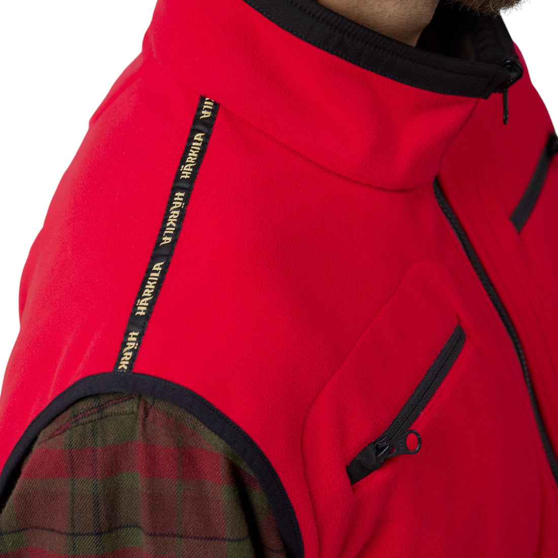 Detalle del cuello alto, hombro y bolsillo del pecho en la cara roja del chaleco Härkila Kamko.